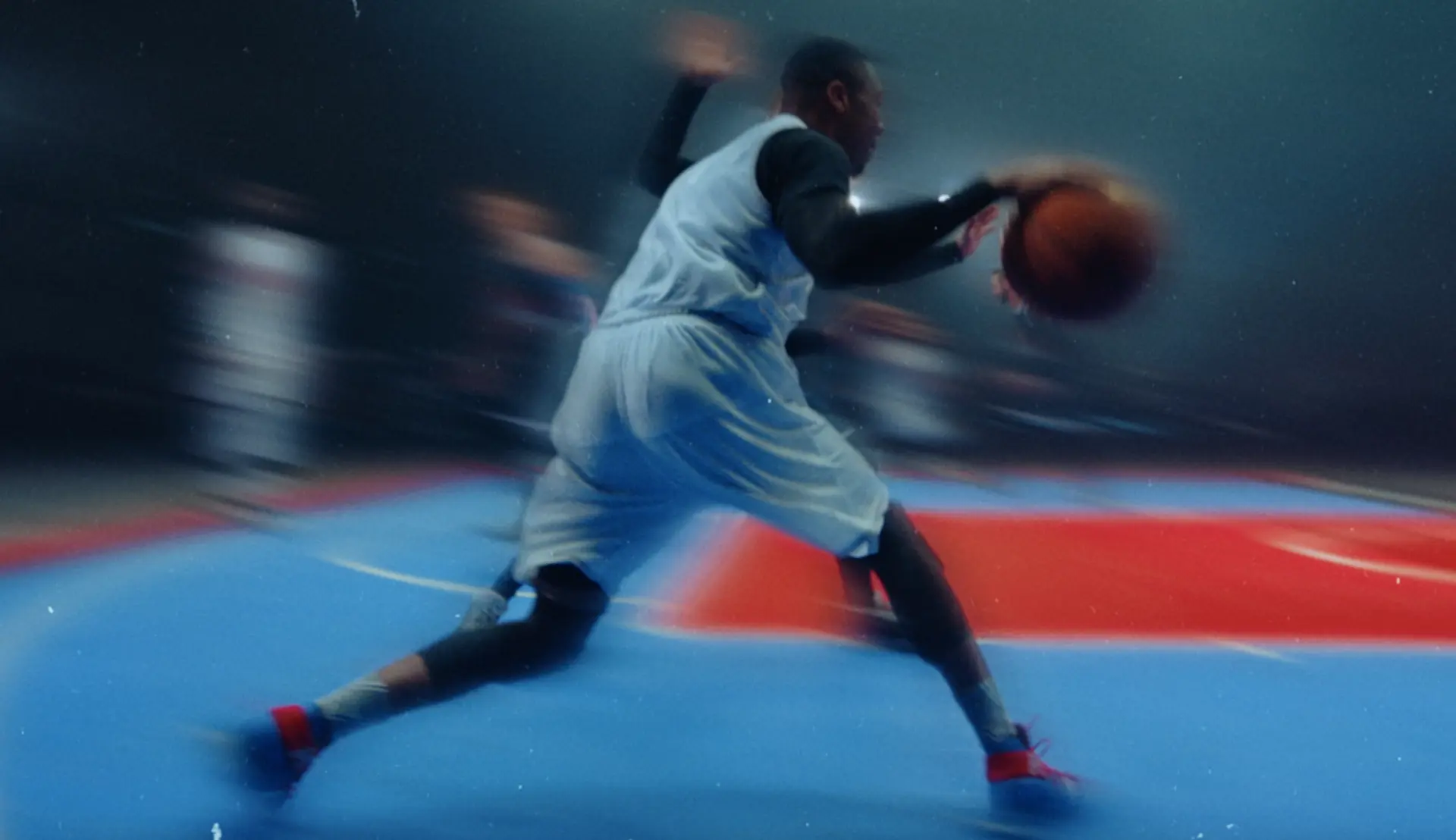 Player driving with the ball in a motion-blurred frame from the Red Bull 3x3 basketball films
